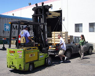 Workers  load the glass onto the truck using the forklift